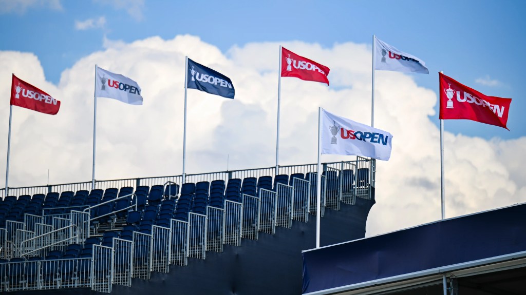 U.S. Open flags flying above empty grandstand seating at Oakmont Country Club during the 2025 championship.