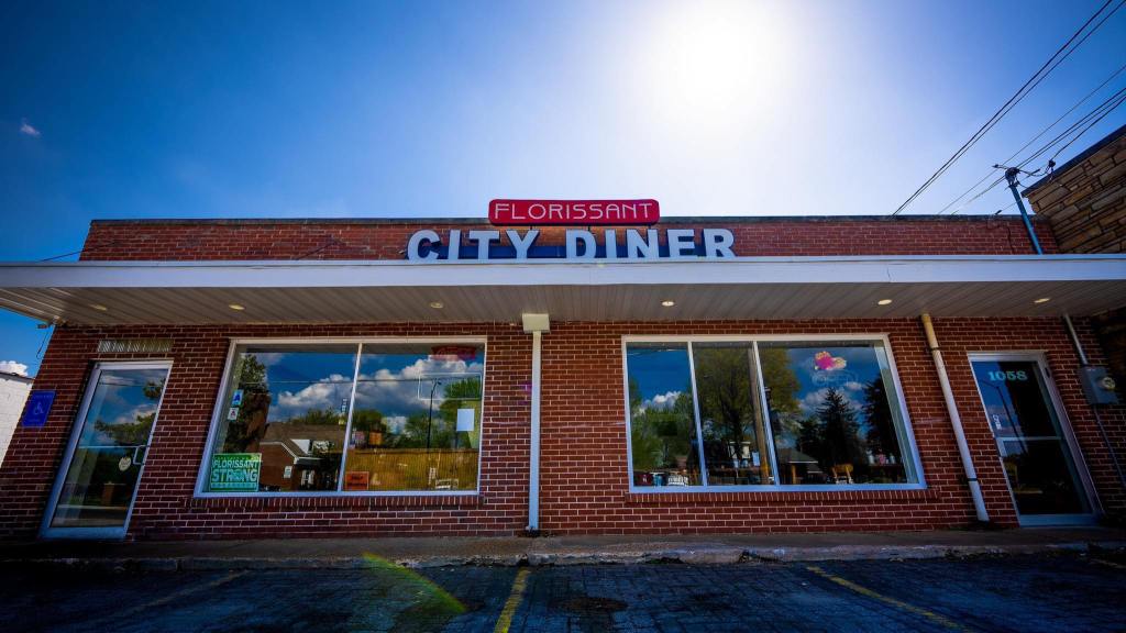 Exterior of Florissant City Diner with red brick facade and large front windows under a bright blue sky.