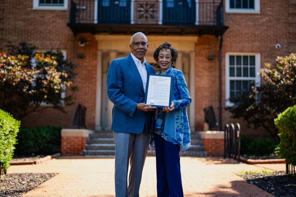 Sam and Sherri Jenkins hold their 50th wedding anniversary proclamation outside a brick building in Florissant, MO.