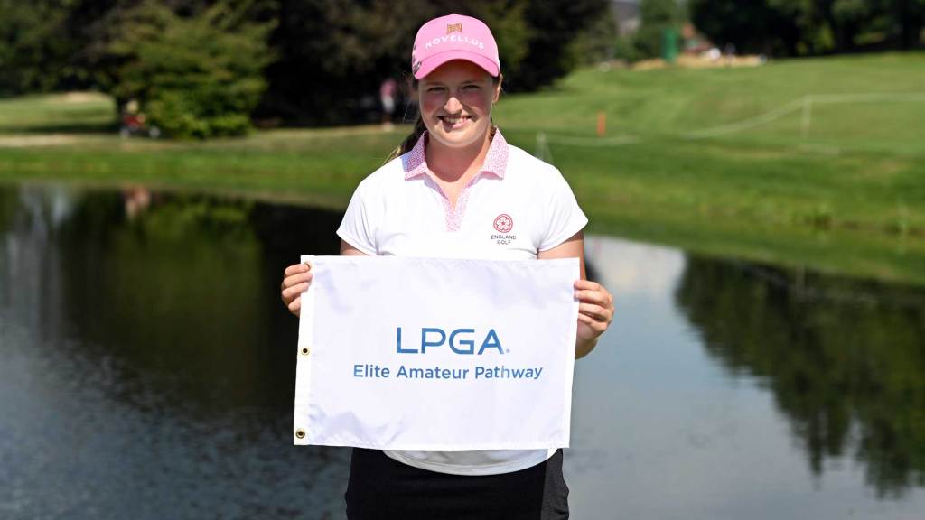 Lottie Woad holds LPGA Elite Amateur Pathway sign at a golf course
